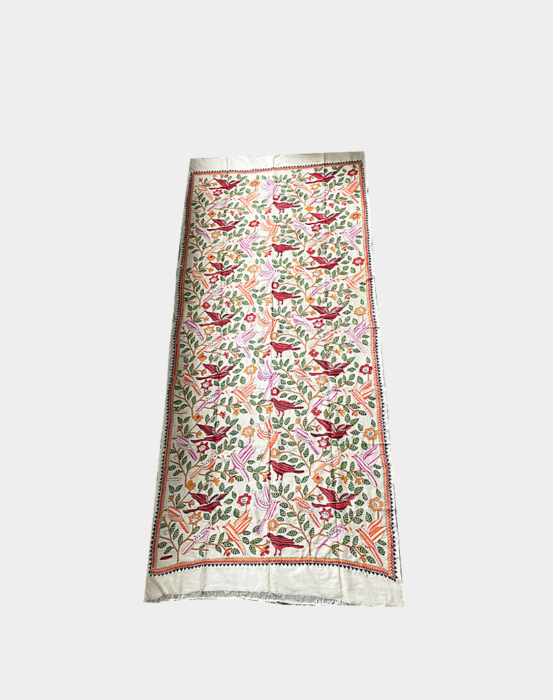 This beautiful vertical Kantha mural is created by hand stitch on a raw tassar silk material. Add spark to the wall of your living room with this Kantha silk embroidered wall tapestry from India.
